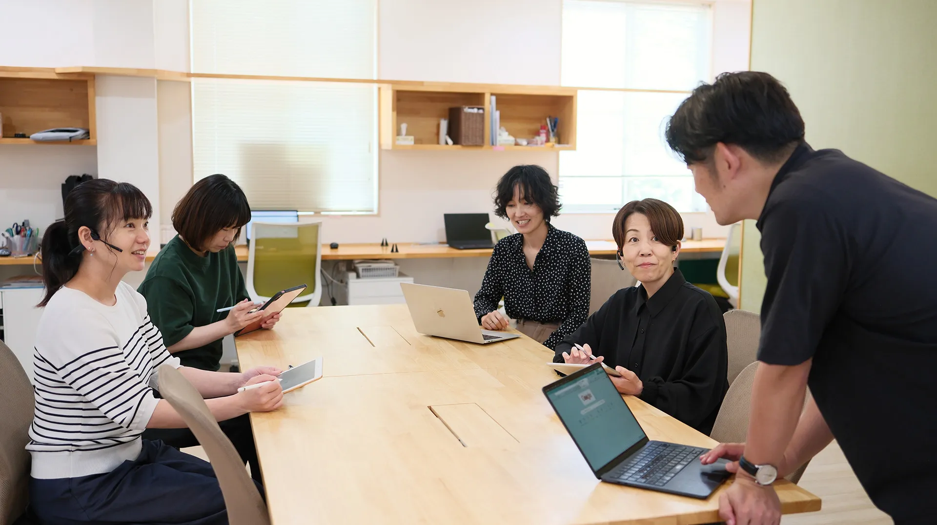 明るいオフィスでノートPCやタブレットを使い打ち合わせをするTTCのスタッフ
